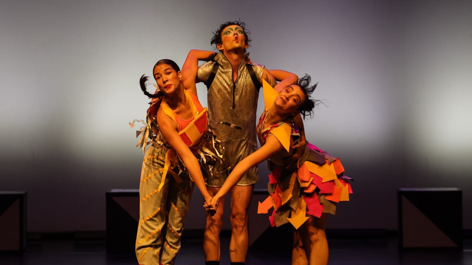 Três bailarinos da Cia. de Dança de São José dos Campos com figurinos coloridos no espetáculo O Mundo de Tludi