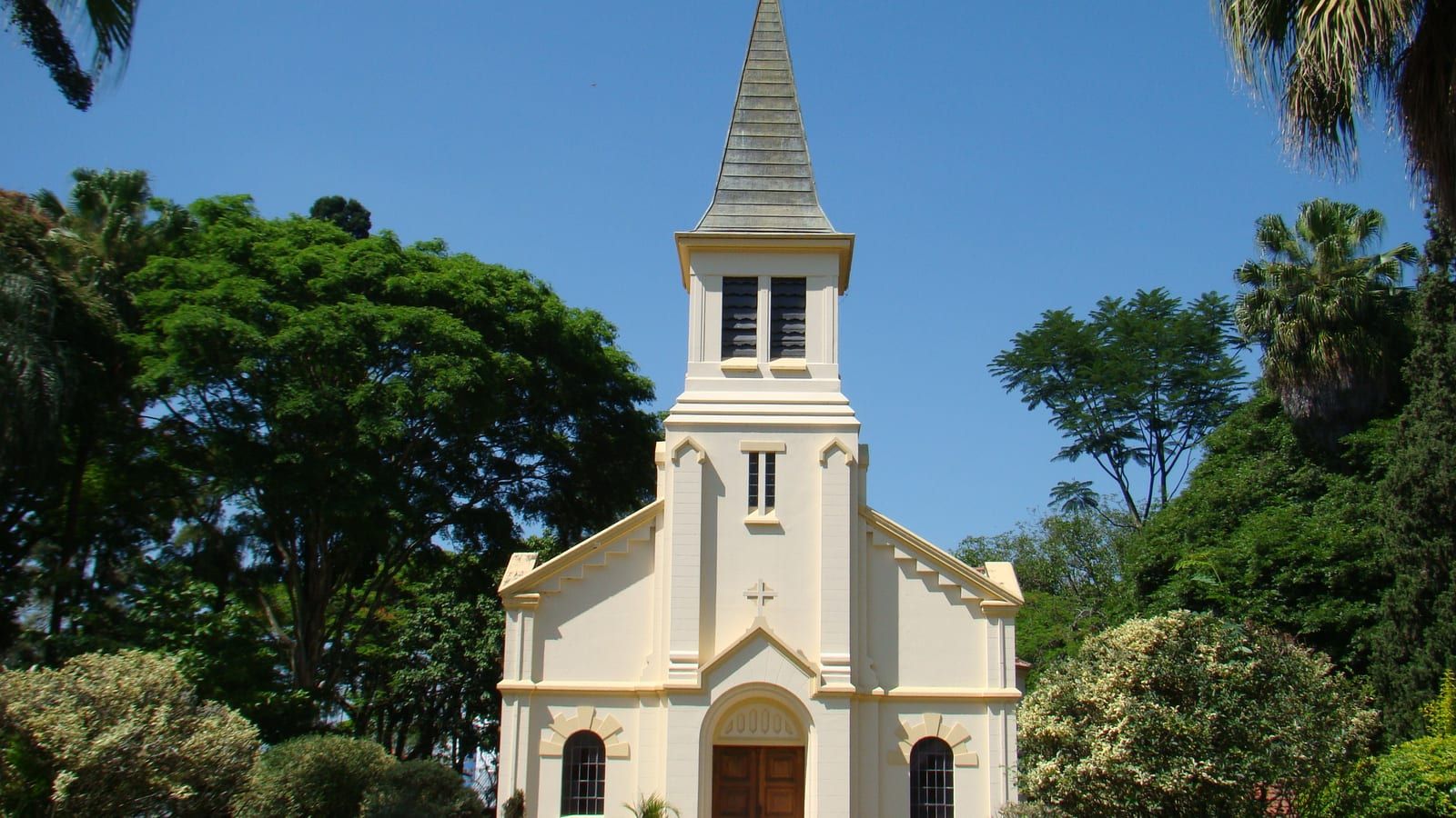Capela do Parque Vicentina Aranha, em São José dos Campos, com torre branca entre palmeiras e árvores