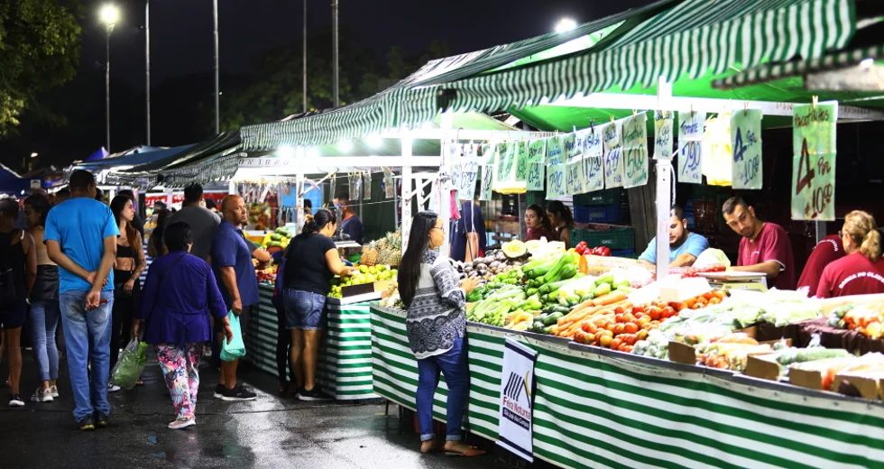 Ilustração de uma feira noturna com barracas de frutas e verduras iluminadas