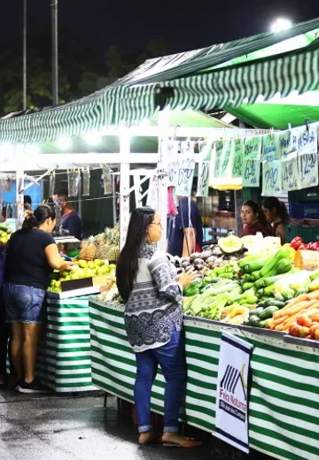 Ilustração de uma feira noturna com barracas de frutas e verduras iluminadas