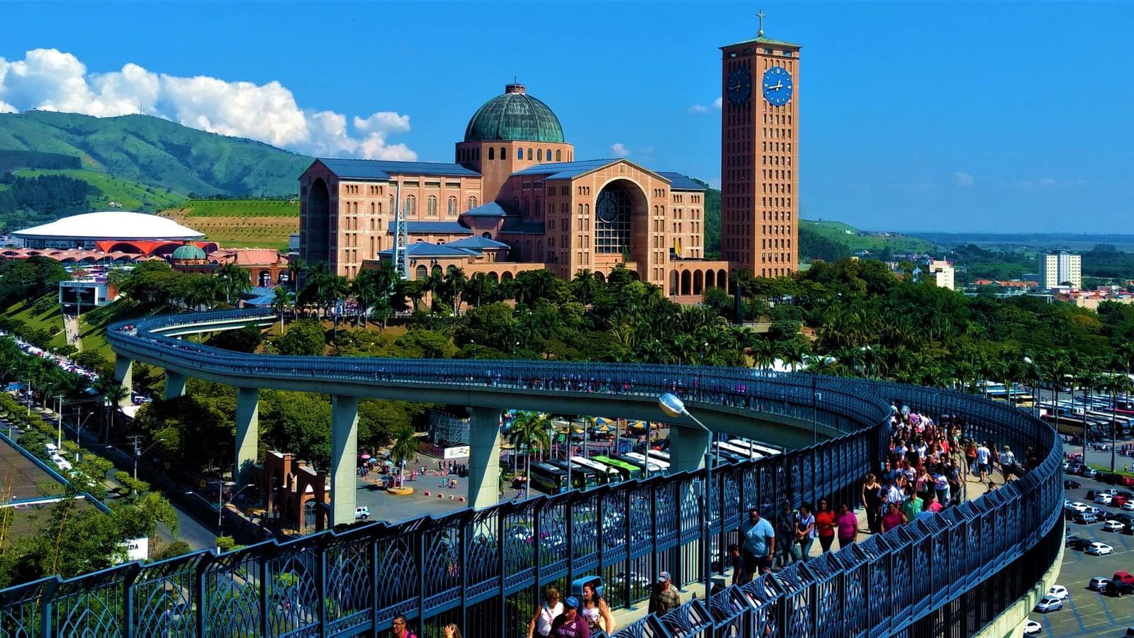 Basílica do Santuário Nacional de Aparecida e a torre do relógio vistas da Passarela da Fé, com romeiros caminhando
