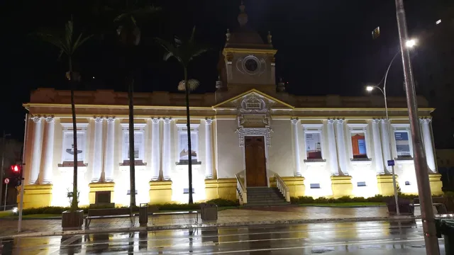 Fachada iluminada à noite do Museu Municipal de São José dos Campos, prédio da antiga Câmara com colunas e torre do relógio