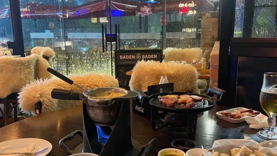 Mesa do Paris Station com fondue e cadeiras forradas de pelego, em Campos do Jordão