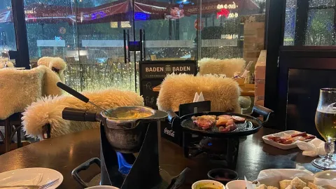 Mesa do Paris Station com fondue e cadeiras forradas de pelego, em Campos do Jordão