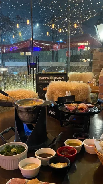 Mesa do Paris Station com fondue e cadeiras forradas de pelego, em Campos do Jordão