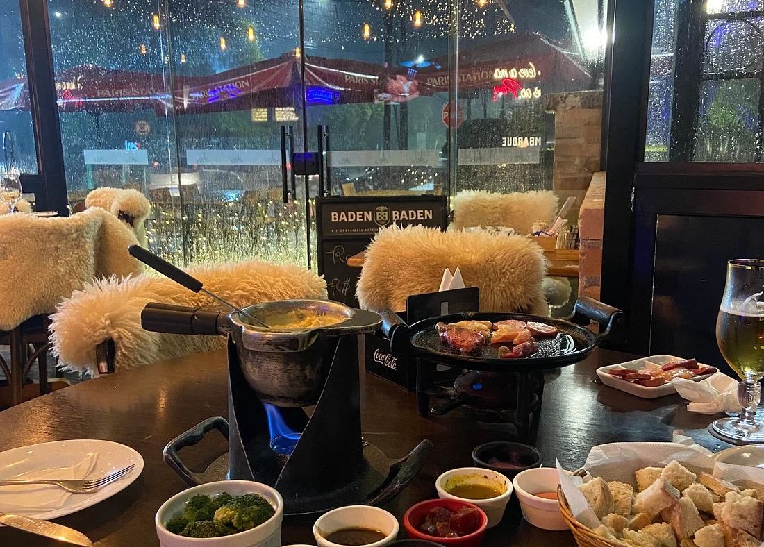 Mesa do Paris Station com fondue e cadeiras forradas de pelego, em Campos do Jordão