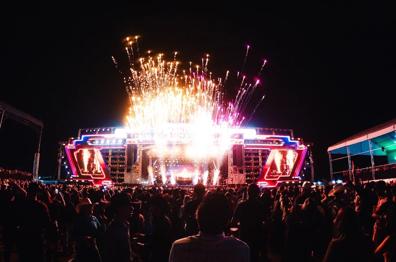 Palco do Taubaté Expo Rodeo iluminado à noite, com telões dos dois lados e a arena lotada, em foto de divulgação do site oficial